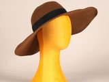 tête de mannequin jaune coiffée d'un chapeau marron orné d'un ruban noir