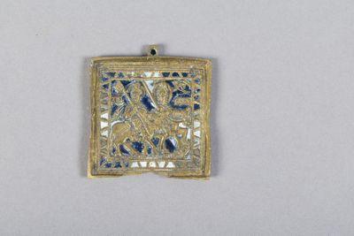 un gros plan d'un pendentif doré et bleu sur une surface blanche