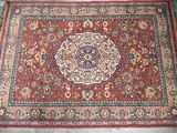 a red rug with a medallion design on it sitting on a cement floor