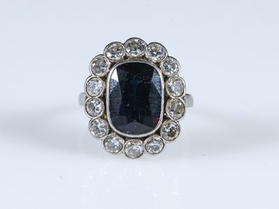 gros plan d'une bague avec une pierre bleue entourée de diamants blancs