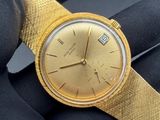 someone is holding a gold watch in their hand on a black glove