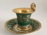a green and gold cup and saucer on a saucer