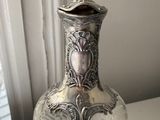 a silver vase that is sitting on a white table
