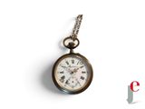 une montre de poche suspendue à une chaîne sur une surface blanche