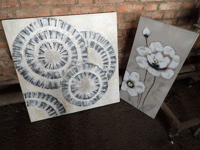 two paintings of black and white flowers on a brick wall