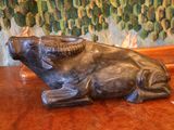 une statue représentant un taureau assis sur une table en bois