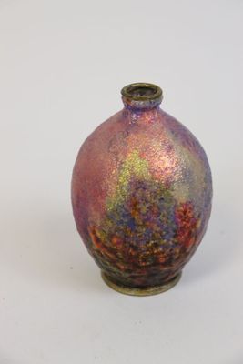 un petit vase posé sur une surface blanche
