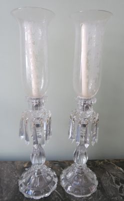 pair of clear glass candlesticks on a table with a white wall in the background