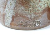 a close up of a brown vase on a white surface