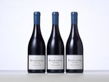 three bottles of red wine sitting on top of a table