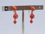 a pair of earrings that are on a metal stand
