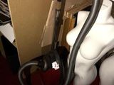 un mannequin blanc avec un aspirateur dans une pièce