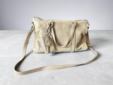 a beige leather handbag sitting on top of a cement floor