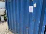 une benne bleue garée devant un immeuble