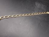 gros plan d'un bracelet en chaîne en or sur une surface noire