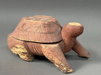 une image représentant une boîte en forme de tortue avec un couvercle, posée sur une surface grise