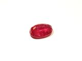 a close up of a red ruby stone on a white surface