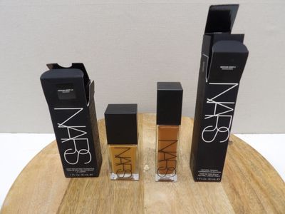 trois flacons de produits cosmétiques Nars posés sur une table en bois