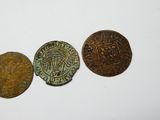 trois pièces de monnaie anciennes posées les unes à côté des autres sur une surface blanche