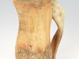 a wooden pitcher with a curved handle on a white surface