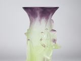 a purple and green vase sitting on a white surface