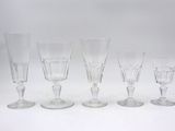six clear wine glasses lined up in a row on a white surface