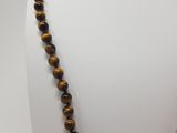 a close up of a tiger eye beaded necklace on a mannequin
