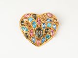 un gros plan sur une broche en forme de cœur ornée de pierres multicolores