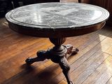 une table au plateau en marbre posée sur un parquet, dans une pièce