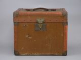 une vieille valise posée sur une table, sur fond gris