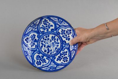 une personne tenant une assiette bleue et blanche à la main