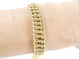 someone is wearing a gold chain bracelet on their arm