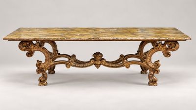 une table richement sculptée, avec un plateau en marbre sur fond blanc