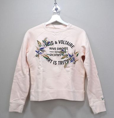 the pink sweatshirt is hanging on a hanger on the wall