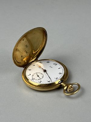 a gold pocket watch sitting on a white surface