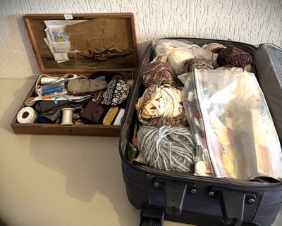 une valise posée sur une table à côté d'une boîte de laine