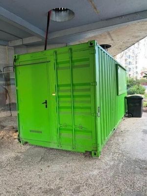 un conteneur vert posé sous un pont, à côté d'une poubelle