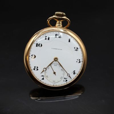 gros plan d'une montre de poche en or sur une surface noire