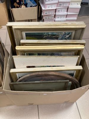 une boîte remplie de photos encadrées, posée par terre dans un magasin