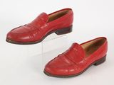 pair of red loafers on clear acrylic stand on white background