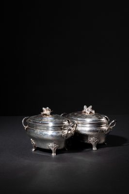 a pair of silver dishes with handles and handles on a black surface
