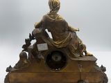 an antique bronze clock with a woman sitting on top of it