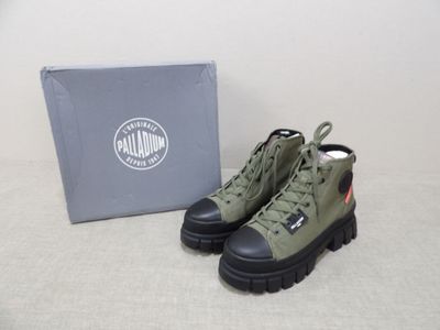 des bottes vertes à semelles noires et une boîte posée sur un fond blanc
