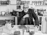 black and white photograph of an older man sitting at a table in a kitchen