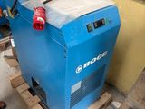 a man standing next to a blue machine on a pallet