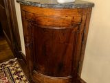 a corner cabinet with a marble top in a room