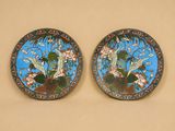 deux assiettes décoratives ornées d'oiseaux et de fleurs sur un fond beige
