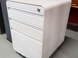 a white filing cabinet sitting on the floor next to a red chair
