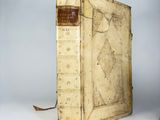 an old book sitting on top of a white table next to a lamp