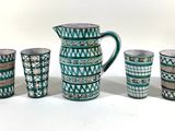 five cups and a pitcher sitting next to each other on a table